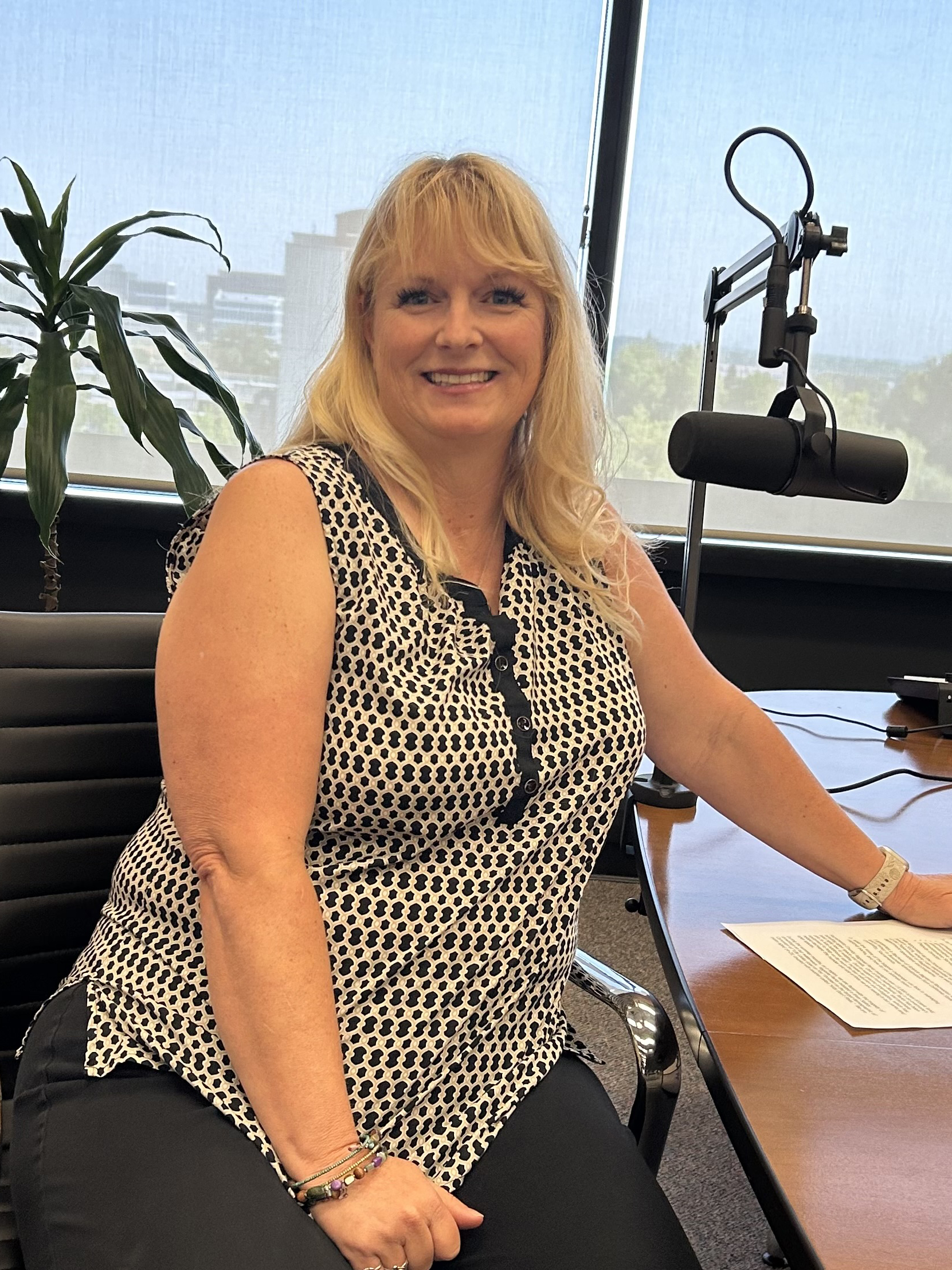 Liz Belas sitting at a podcast table